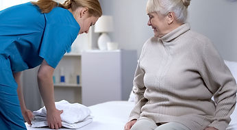 nurse-preparing-clean-bedlinen-to-elderly-female-patient-in-medical-picture-id1150489856.j