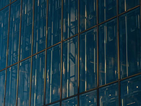 Glasfassade eines modernen Bürogebäudes mit goldenen Stahlstreben in Navy und Gold – Symbol für strukturierte Vermögensplanung und Unternehmensbesteuerung