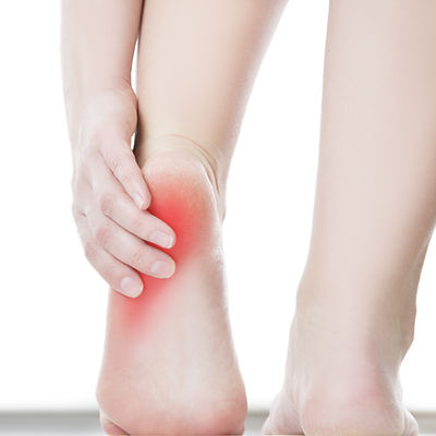 A person holding their heel with the pain indicated in red
