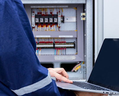 elektrik sistemlerini kontrol eden bir işçi elinde dizüstü bilgisayar tutuyor