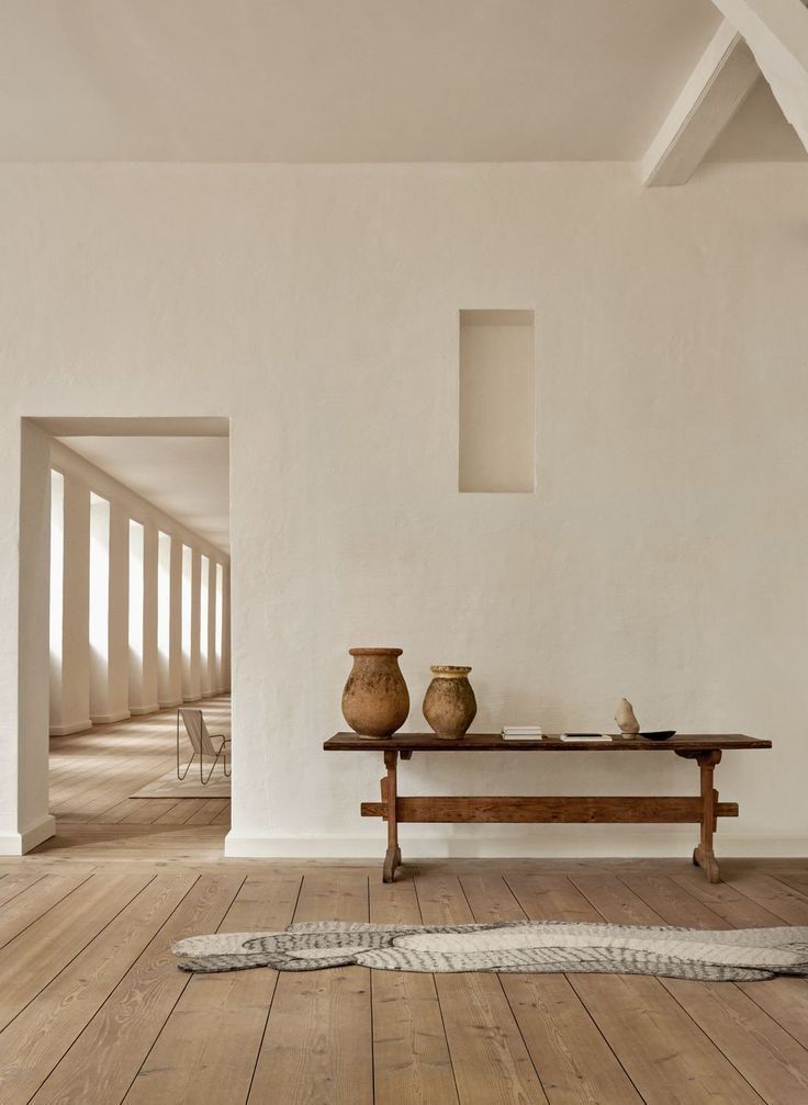 Minimalist interior in neutral tones with bench and terracotta jars