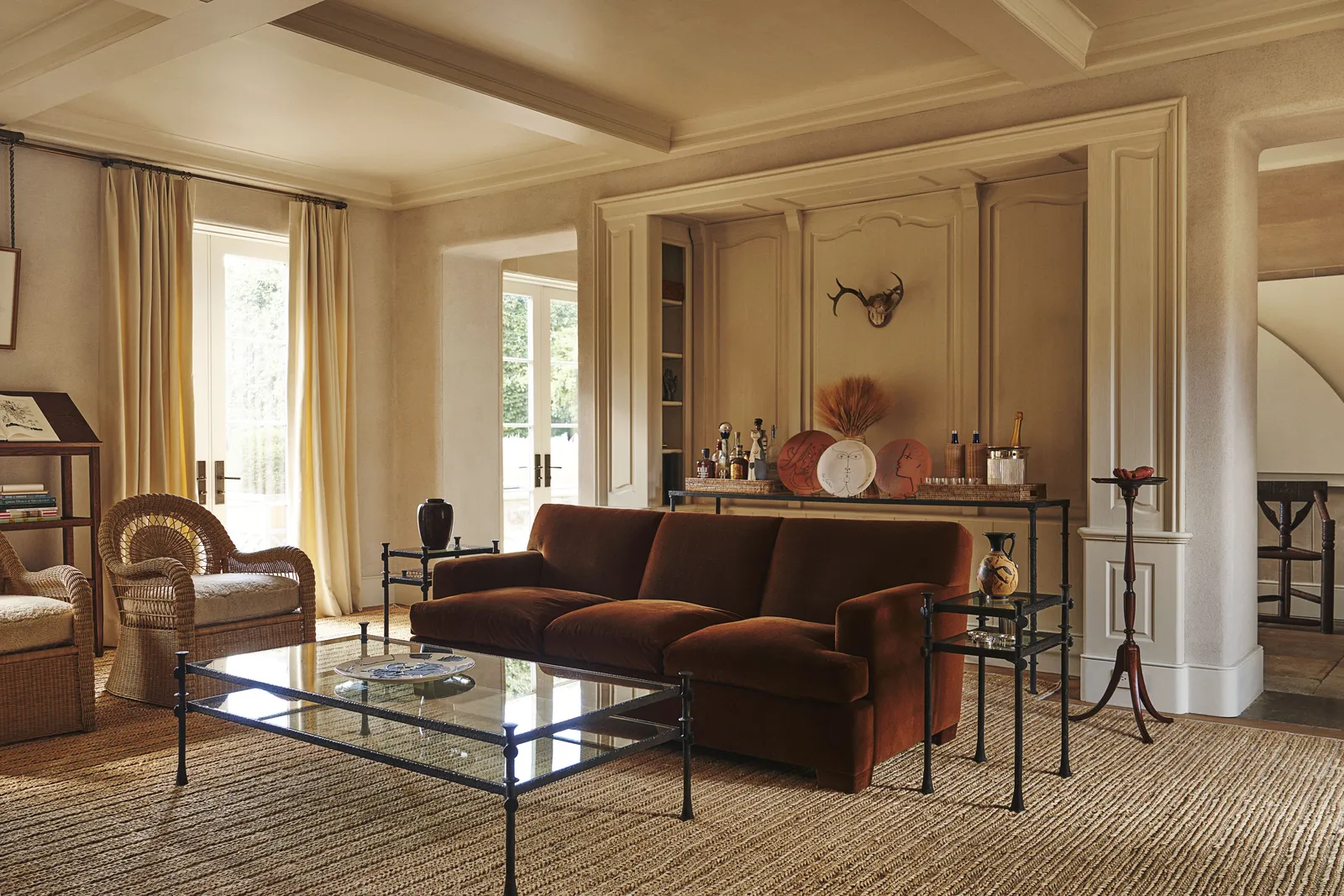 Salon beige et brun, canapé en velours, lumière douce sur mobilier tressé.