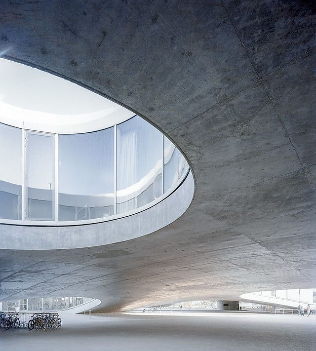  Interior view of the Rolex Learning Center by SANAA in Lausanne, curved concrete roof with circular openings flooding the space with natural light.