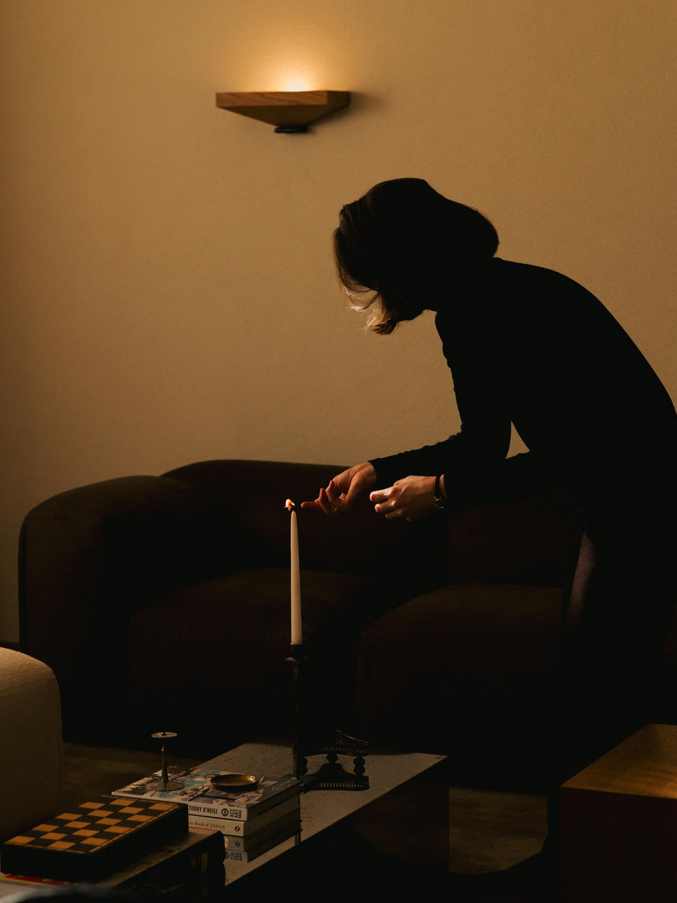 BMA Appartement par Agata Melerska, avec table basse, bougie, fauteuils sombres et lumière chaude.