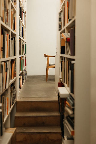 Architectural photography by Maureen M. Evans for Architectural Digest — library shelves framing a single wooden chair.