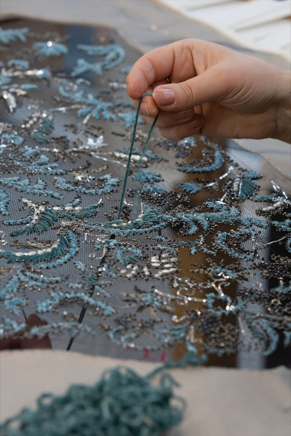 Artisanal embroidery for Dior Haute Couture Spring-Summer 2024, turquoise threads and silver beads on black tulle.