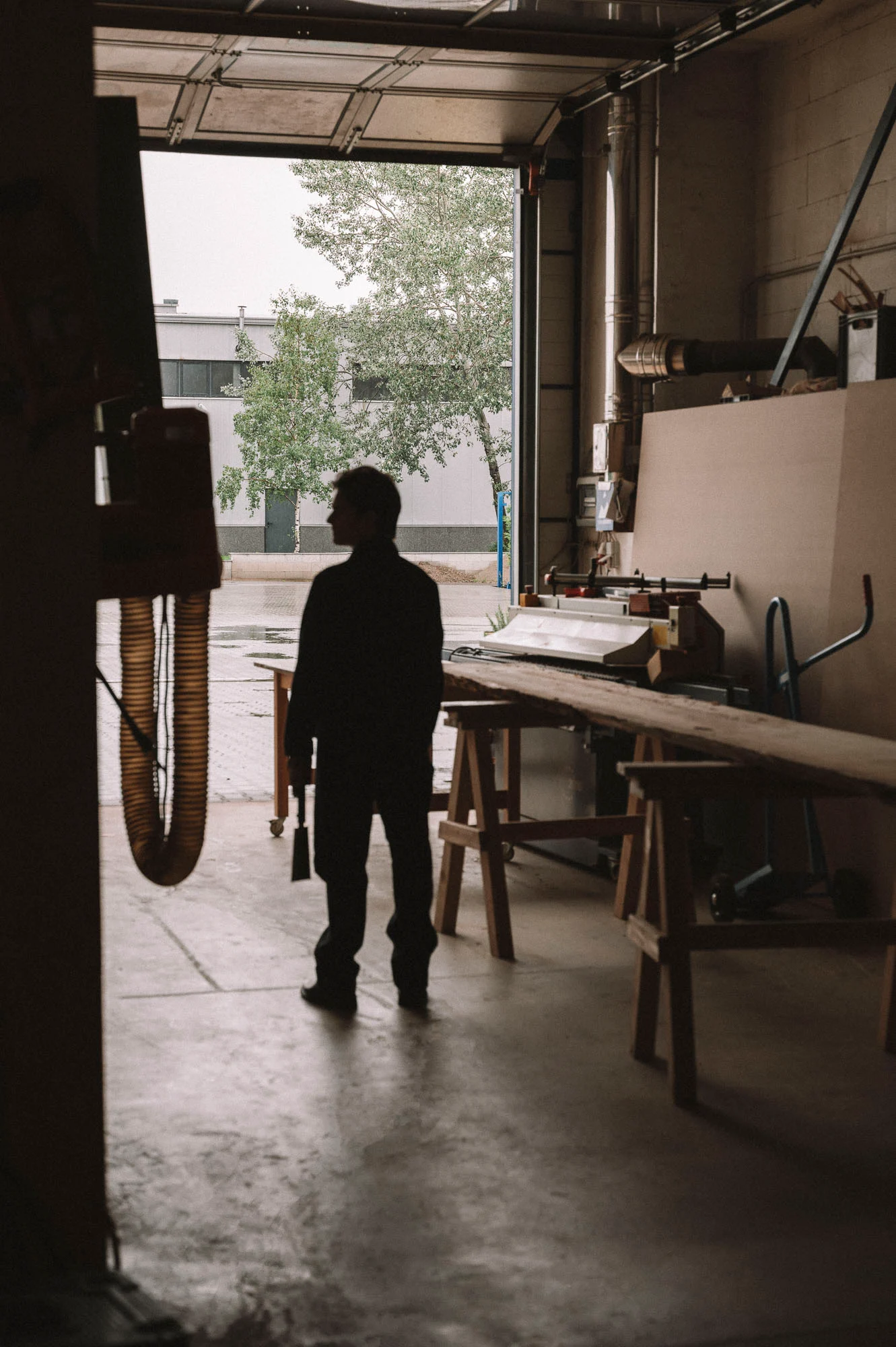 Atelier de menuiserie avec silhouette et bois en cours de travail, design intérieur artisanal - Karst Berlin.