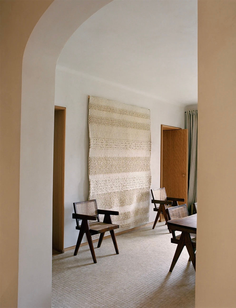 Appartement sur la Rive Gauche à Paris — Salle à manger avec chaises en bois et cannage, tenture murale tissée et sol en mosaïque claire.