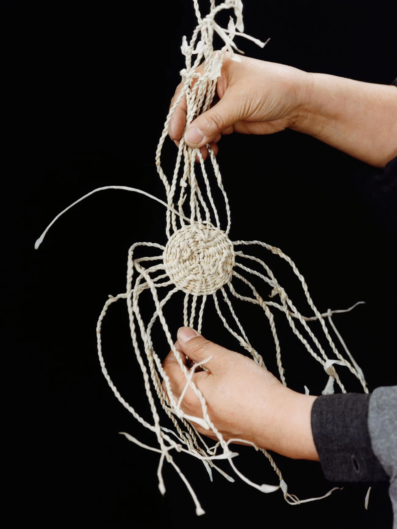 Hands weaving natural fibers for Loewe Craftsmanship.