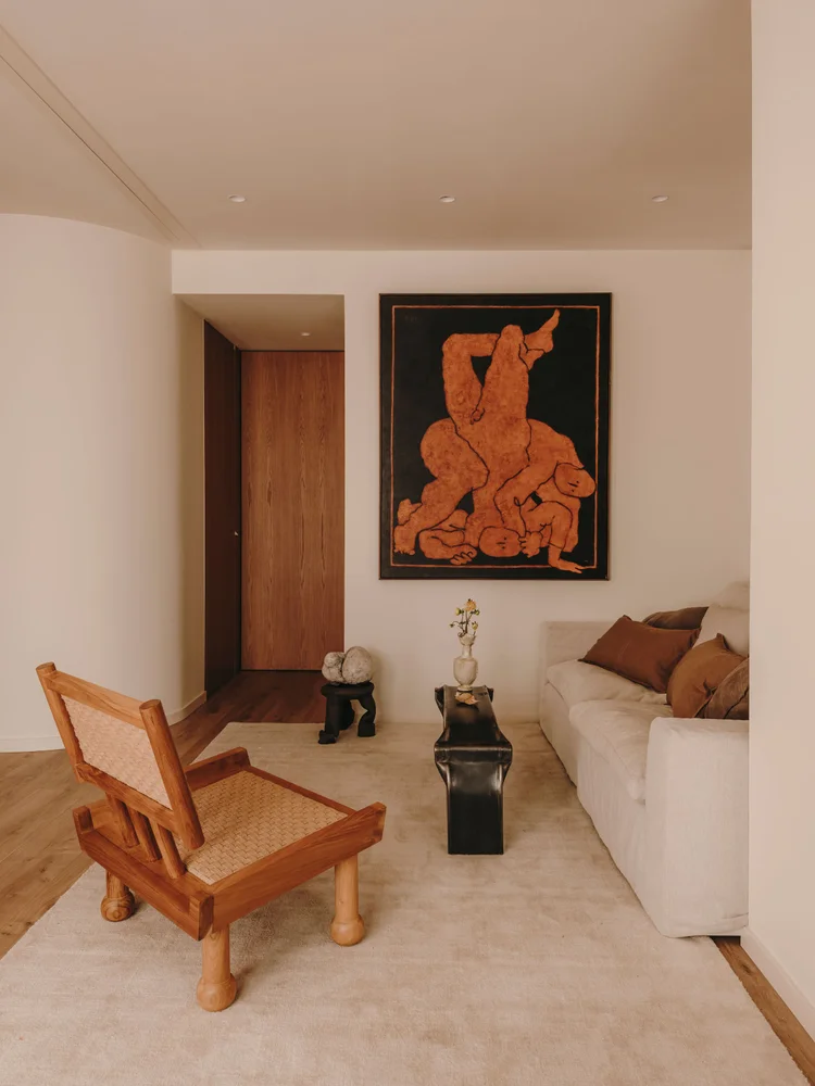 Living room of Arcadia by Santa Living and MA&Partners, with a wooden armchair, light sofa, wall artwork and black coffee table.