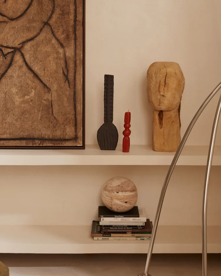 Shelf in Apartment 92 by Santa Living, with wall artworks, sculptures, books and a chrome lamp.
