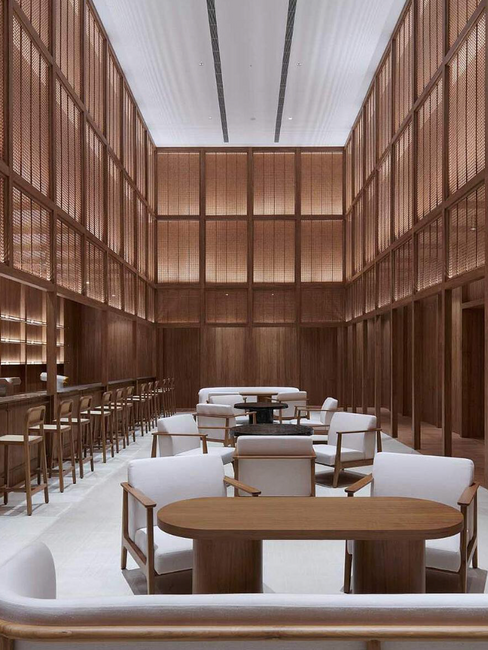 Intérieur du Sanya Wellness Retreat par Neri&Hu, avec panneaux en bois, assises claires et lumière indirecte.