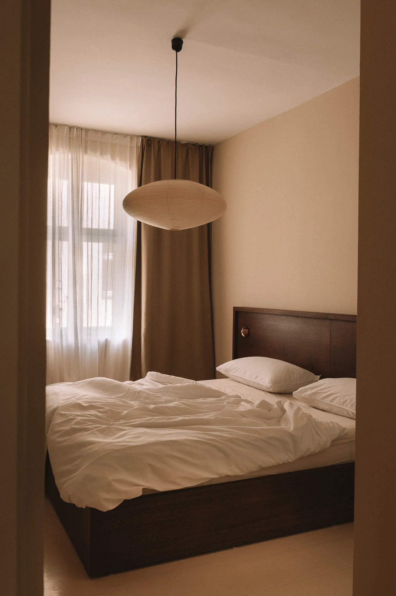 Chambre minimaliste avec lit en bois et suspension papier, design intérieur - Karst Berlin.