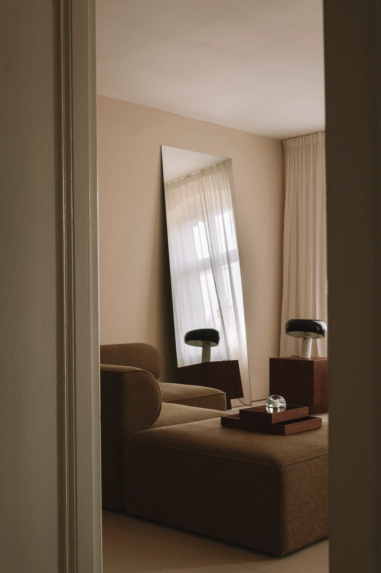 Salon minimaliste avec miroir incliné et canapé textile, architecture intérieure - Karst Berlin.