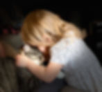 little girl snuggling up to her gray tabby cat
