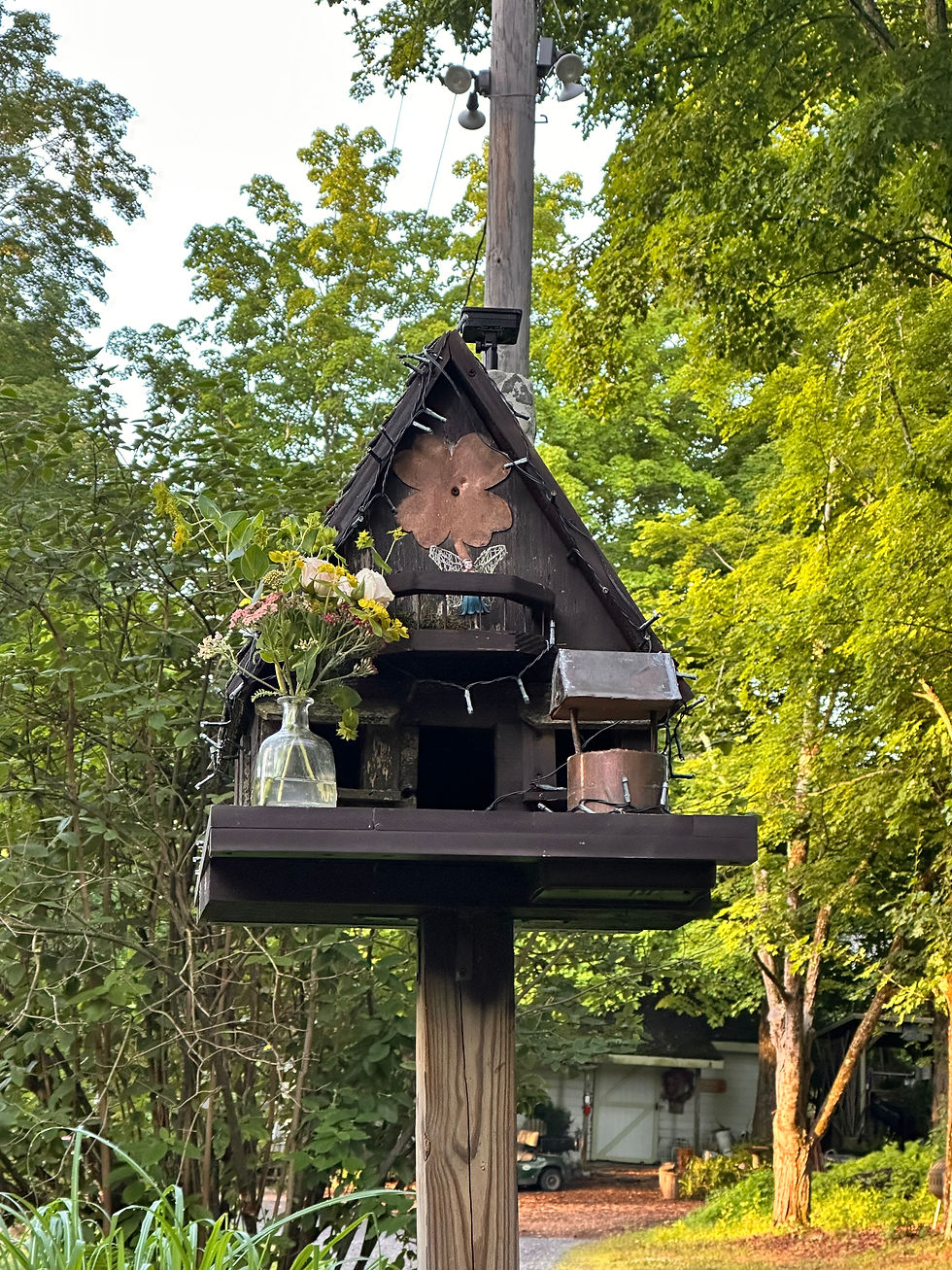 a bird house with decorations of a little well, fairy lights, and a small flower vase