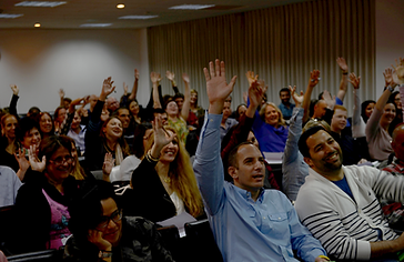 תמונה של אנשים בקהל מרימים  את היד למעלה