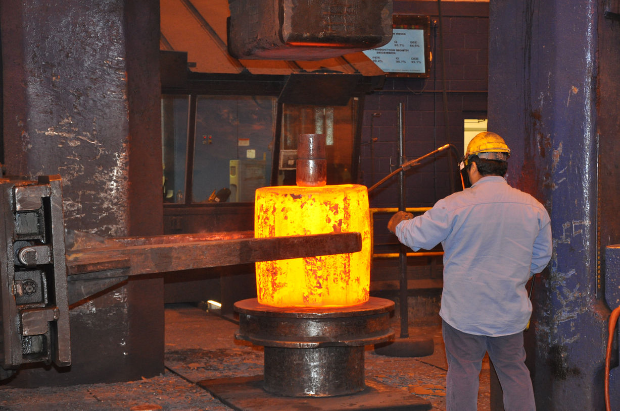 Ring preform with a worker punching a hole in the middle to create a hollow