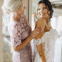 mother of the bride buttoning up bride's dress