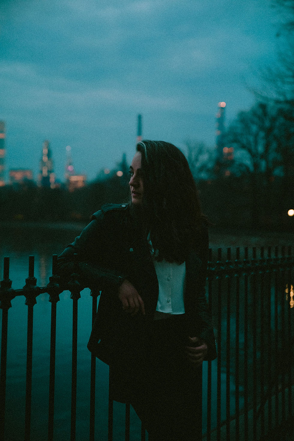 A very cinematic blue hour portrait of a woman in front of the NYC skyline