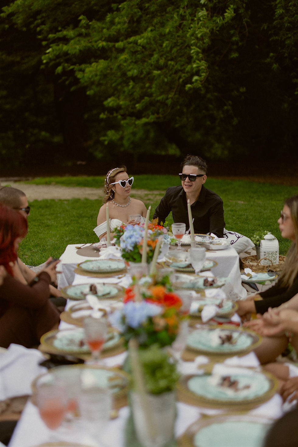 couple enjoys a central park picnic with their wedding party after their ceremony