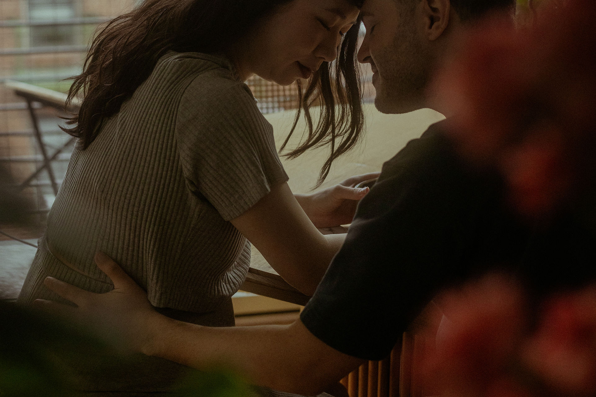 Couple puts heads together in intimate way at kitchen table over coffee