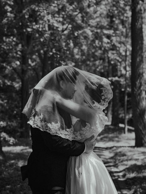 bride and groom under veil holding onto one another