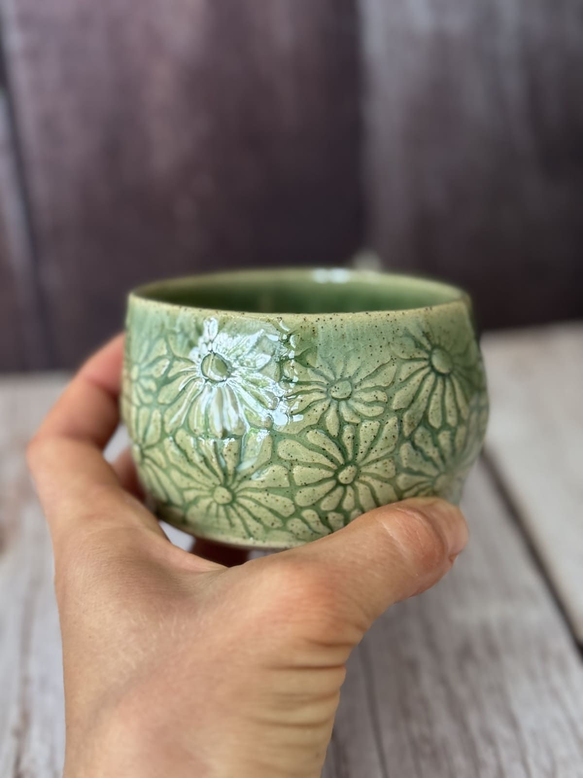Hand holds a green daisy-print hug mug