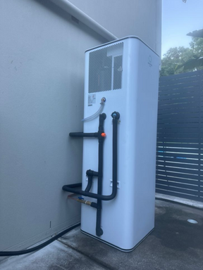Hot water system installed on the exterior of a property behind a fence.