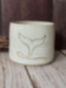 Speckled white hug mug with line-drawn gold whale tail going into the water