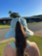 Thumbnail: Girl wearing a pastel teal ponytail bucket hat with white Seeking Paradise logo.