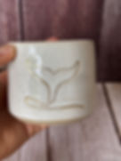 Speckled white hug mug with line-drawn gold whale tail going into the water
