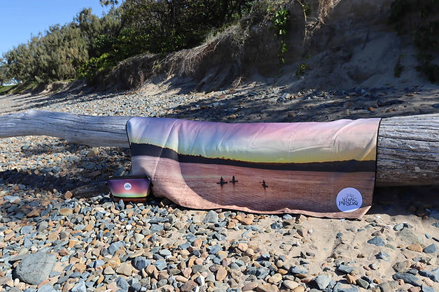 Kichant dam sunset microfibre towel on a log at a rocky beach