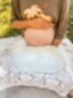 Woman sitting with pregnant belly, holding white belly bowl