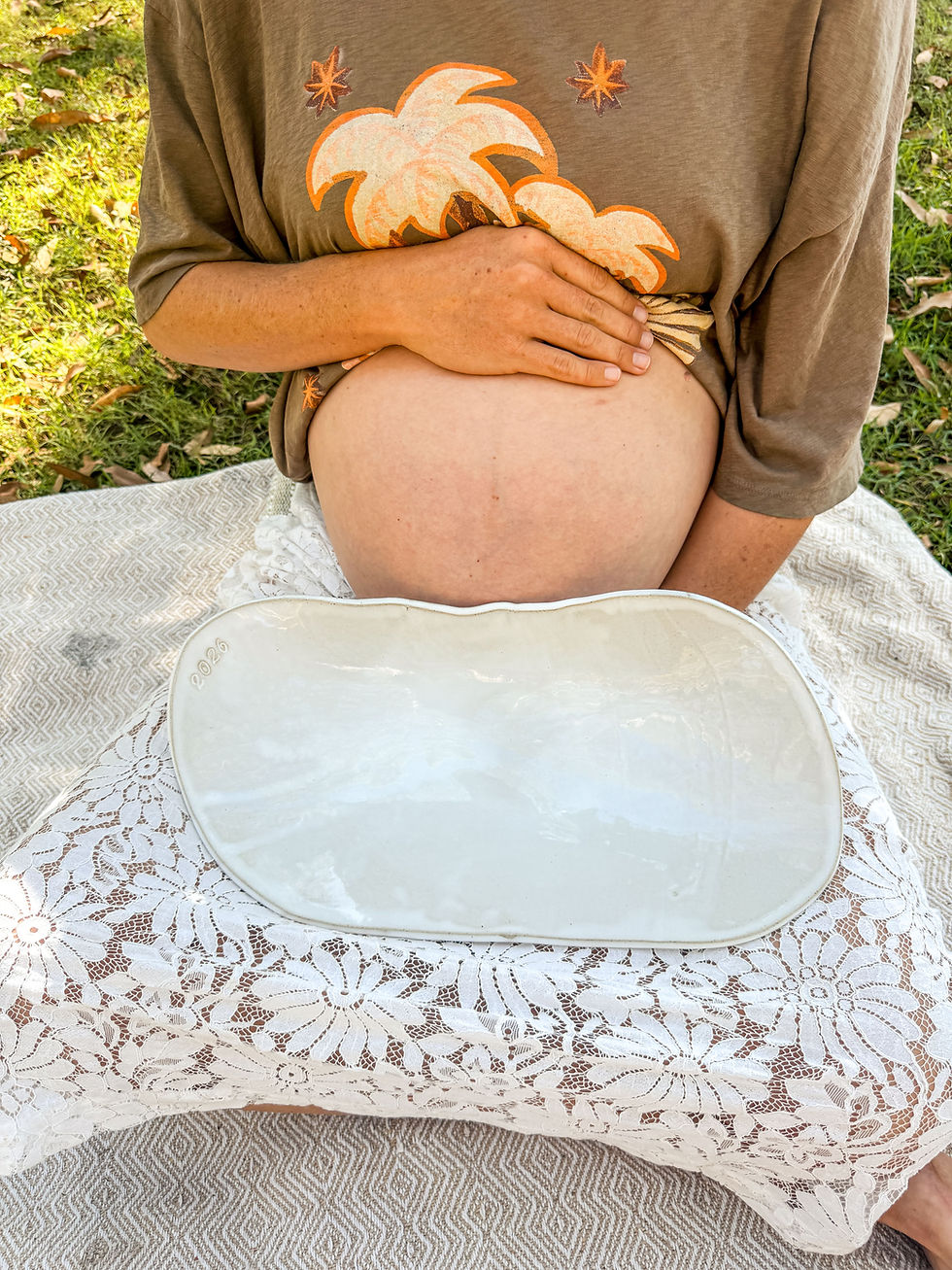 Woman sitting with pregnant belly, holding white belly bowl