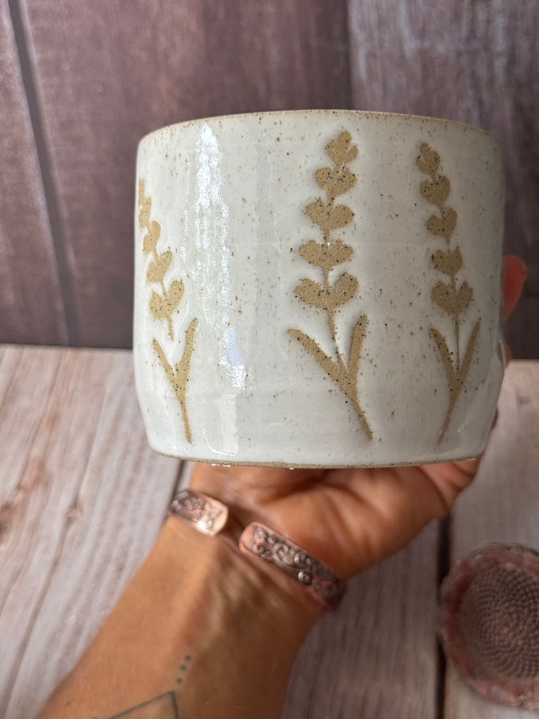 White speckled clay mug with lavender sprigs placed around the design revealing the natural clay