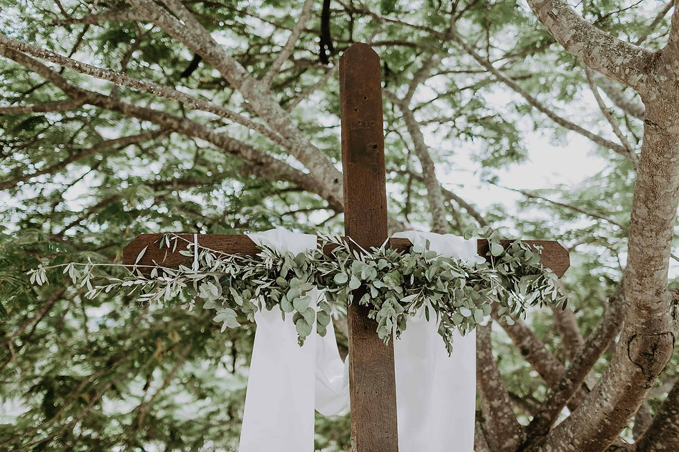Timber cross arbour adorned with greenery and a white fabric drape