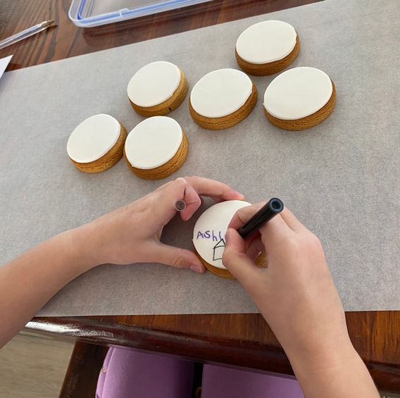 Child's hands decorating white biscuits