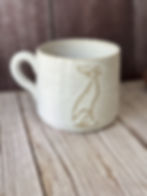 White ceramic speckled clay mug with line art of a dog drawn on it
