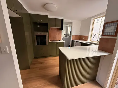 Olive green resurfaced kitchen with white benchtops in a Gold Coast townhouse