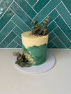 Two-tone green and white cake with florals to the side and top