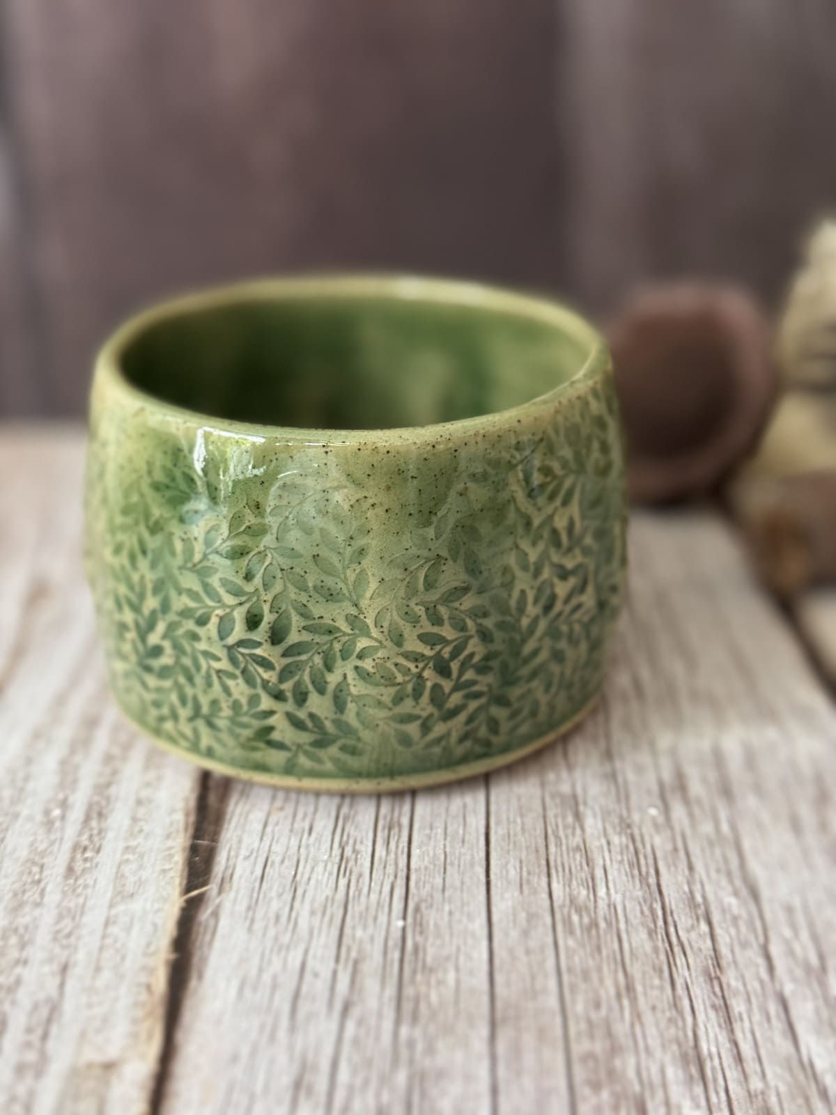 Handmade wonky hug mug with leaves impressed in the light olive green glaze