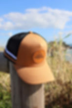Tan Trucker hat with black mesh and tan circle Seeking Paradise logo.