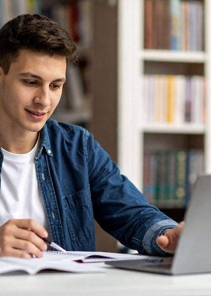 Young man working at a desk with a notepad, pen and computer