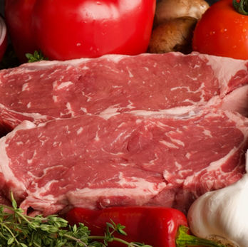 Two beef ribeye steaks surrounded by fresh vegetables