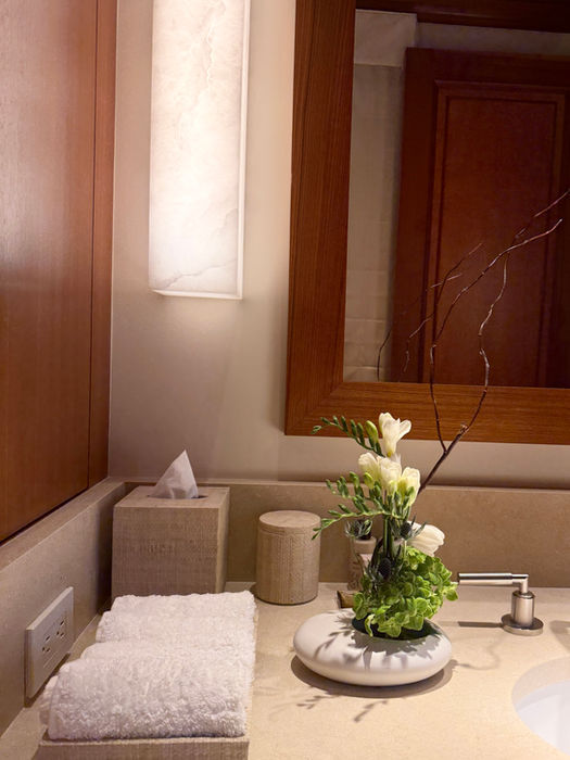 Minimalist white floral arrangement with green hydrangeas, delicate branches, and modern Japanese-inspired styling displayed on a luxury bathroom vanity.