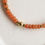 Thumbnail: Closeup van statement kralen ketting met oranje en gouden, stainless steel kralen