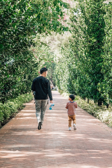 Daddy and son at Lai Chi Kok Park playing strolling in the tree-lined path.
