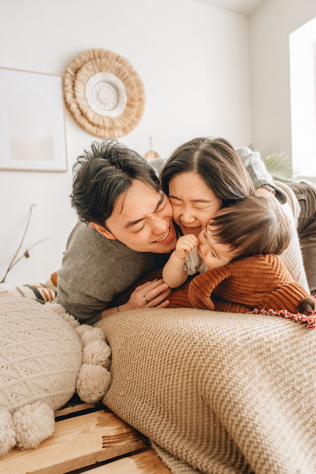 Family of 3 taking a picture together on bed