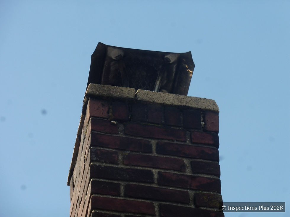 Top of a brick chimney with a rusted and distorted metal cap and a cracked, spalling concrete crown above the flue.